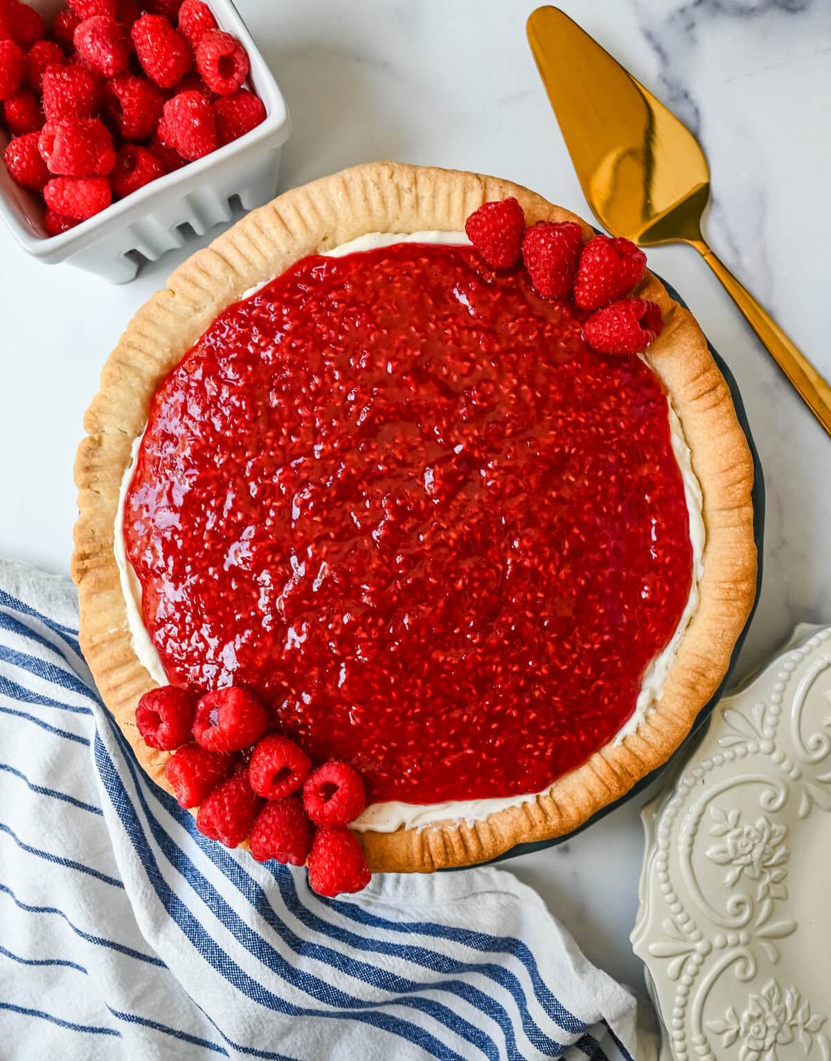 This homemade Raspberry Cream Pie is made with a sweet vanilla cream cheese cheesecake filling topped with a homemade raspberry sauce, all in a buttery, flaky homemade crust. This is a homemade take on the famous Briermere Farms raspberry cream pie and the perfect summer dessert that can be made with fresh or frozen raspberries.