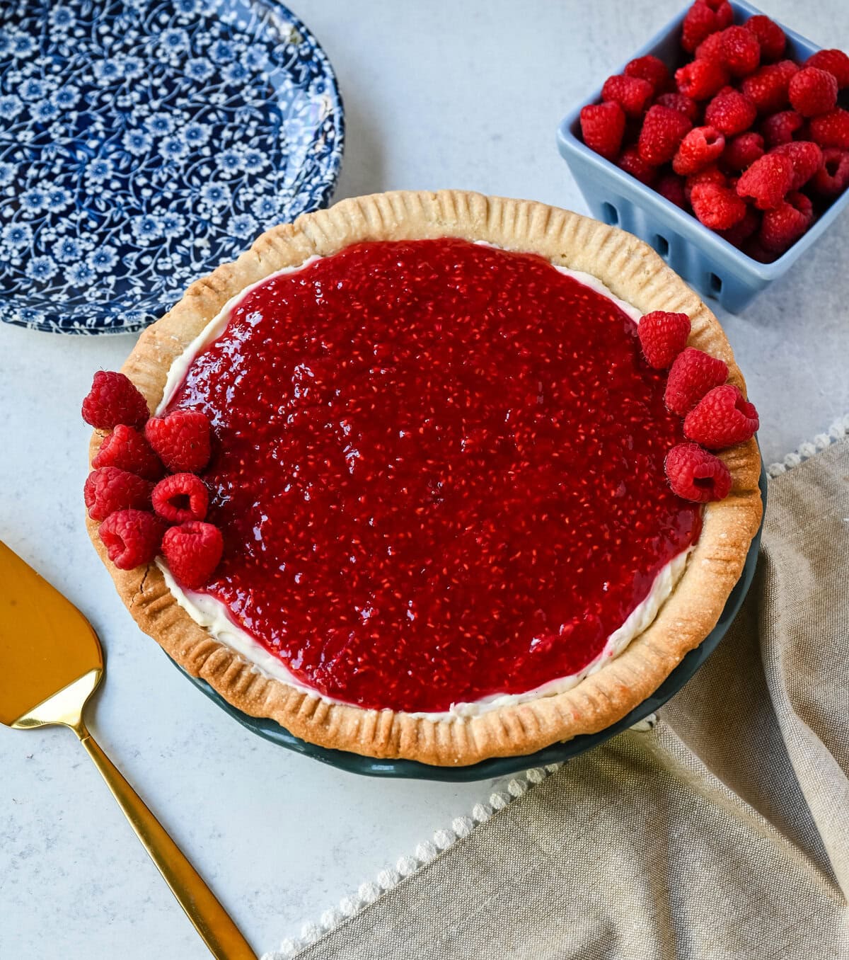 This homemade Raspberry Cream Pie is made with a sweet vanilla cream cheese cheesecake filling topped with a homemade raspberry sauce, all in a buttery, flaky homemade crust. This is a homemade take on the famous Briermere Farms raspberry cream pie and the perfect summer dessert that can be made with fresh or frozen raspberries.