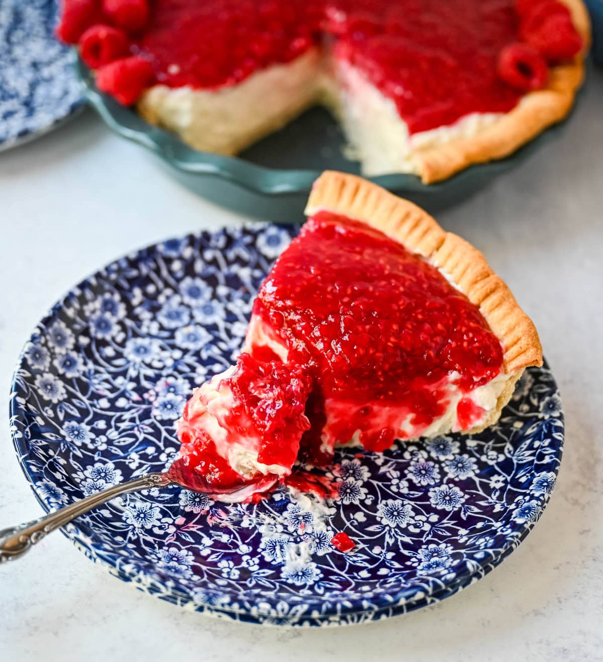 This homemade Raspberry Cream Pie is made with a sweet vanilla cream cheese cheesecake filling topped with a homemade raspberry sauce, all in a buttery, flaky homemade crust. This is a homemade take on the famous Briermere Farms raspberry cream pie and the perfect summer dessert that can be made with fresh or frozen raspberries.