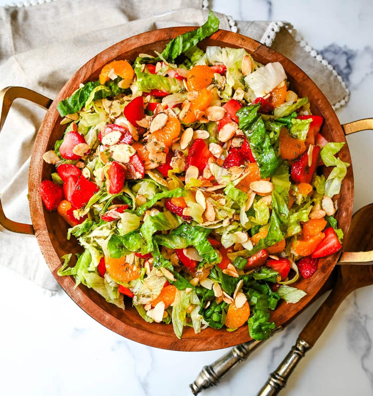 A fresh strawberry mandarin orange salad with candied almonds is the perfect summer side dish! Sweet strawberries, mandarin oranges, crunchy candied almonds, and a light homemade dressing.