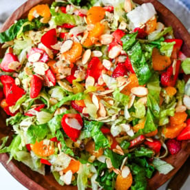 A fresh strawberry mandarin orange salad with candied almonds is the perfect summer side dish! Sweet strawberries, mandarin oranges, crunchy candied almonds, and a light homemade dressing.