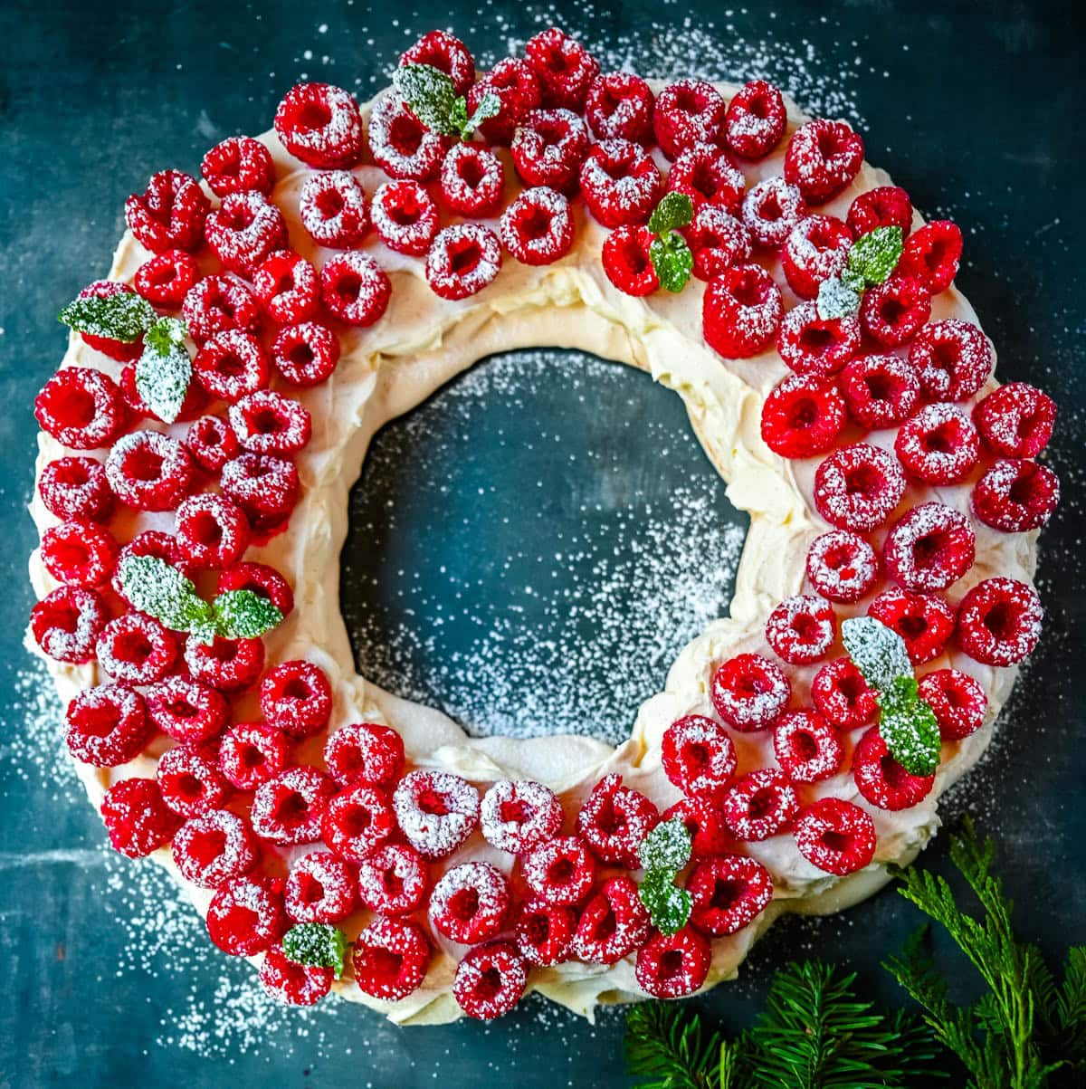 This Christmas Pavlova is a show-stopping holiday dessert with a crisp meringue shell, marshmallow-soft center, and dreamy mascarpone whipped cream piled high with fresh raspberries. A gorgeous Christmas dessert that feels fancy but is actually foolproof.