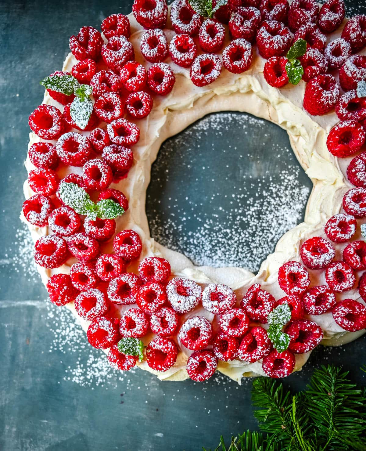 This Christmas Pavlova is a show-stopping holiday dessert with a crisp meringue shell, marshmallow-soft center, and dreamy mascarpone whipped cream piled high with fresh raspberries. A gorgeous Christmas dessert that feels fancy but is actually foolproof.