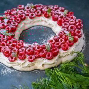 This Christmas Pavlova is a show-stopping holiday dessert with a crisp meringue shell, marshmallow-soft center, and dreamy mascarpone whipped cream piled high with fresh raspberries. A gorgeous Christmas dessert that feels fancy but is actually foolproof.