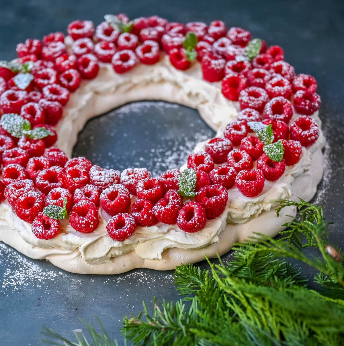 This Christmas Pavlova is a show-stopping holiday dessert with a crisp meringue shell, marshmallow-soft center, and dreamy mascarpone whipped cream piled high with fresh raspberries. A gorgeous Christmas dessert that feels fancy but is actually foolproof.