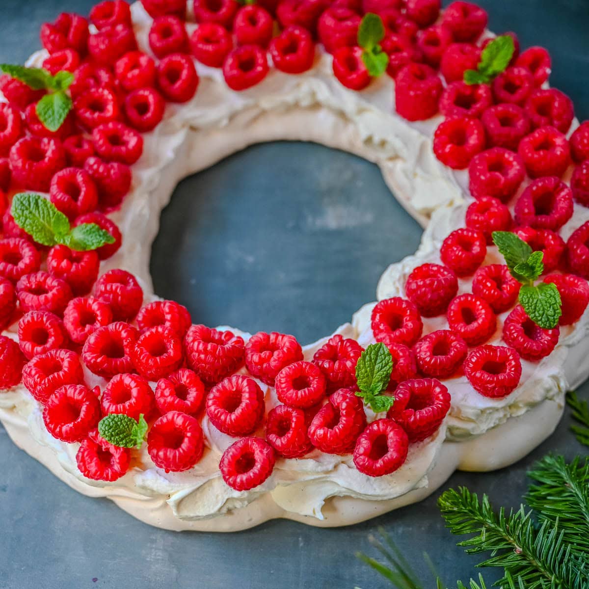 This Christmas Pavlova is a show-stopping holiday dessert with a crisp meringue shell, marshmallow-soft center, and dreamy mascarpone whipped cream piled high with fresh raspberries. A gorgeous Christmas dessert that feels fancy but is actually foolproof.