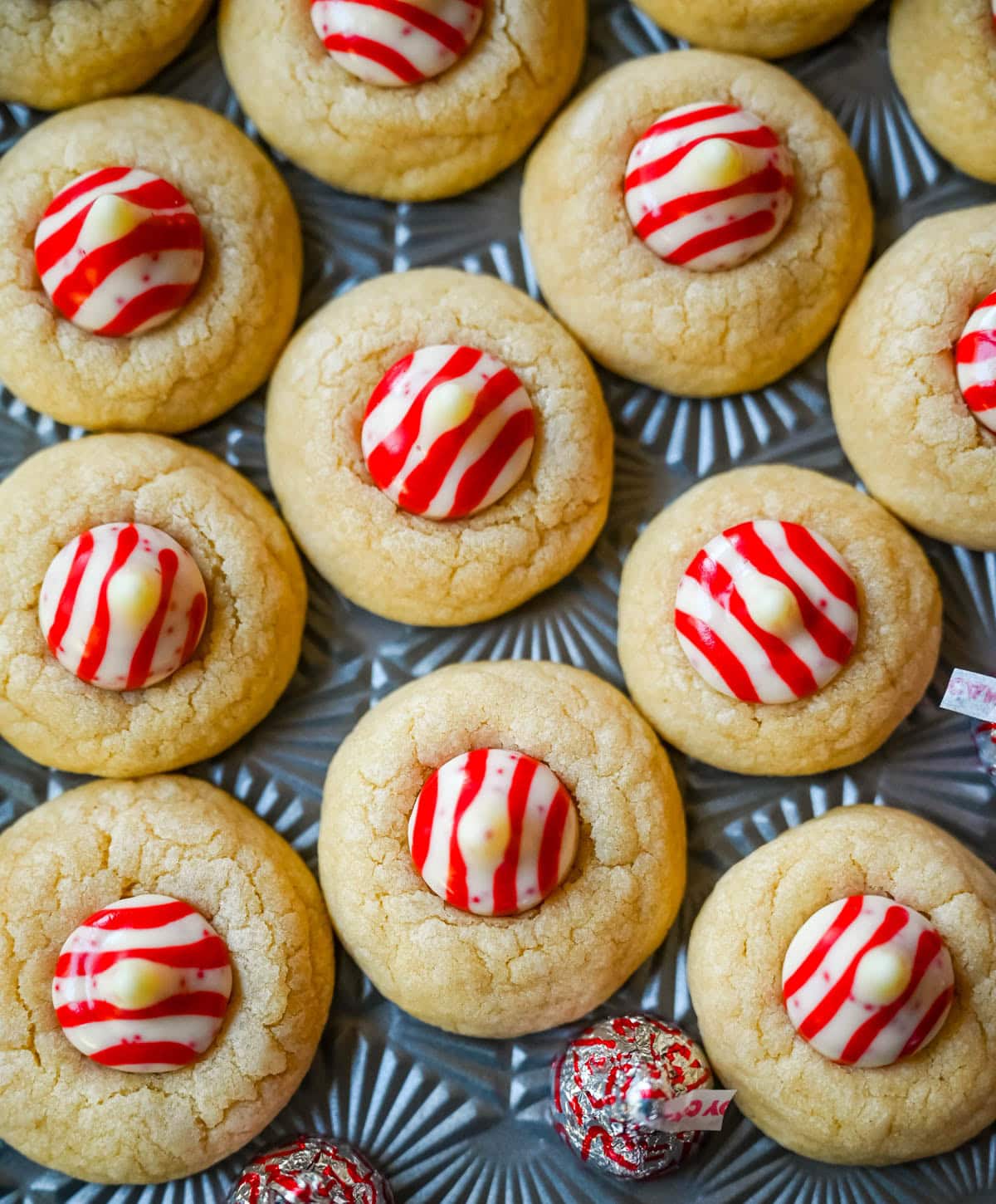 These Candy Cane Kiss Cookies are soft, buttery sugar cookies rolled in sparkling sugar or festive sprinkles, baked until just set, and then pressed with a striped peppermint Candy Cane Kiss right in the center. This Peppermint Kiss Cookie is such a festive Christmas cookie recipe.