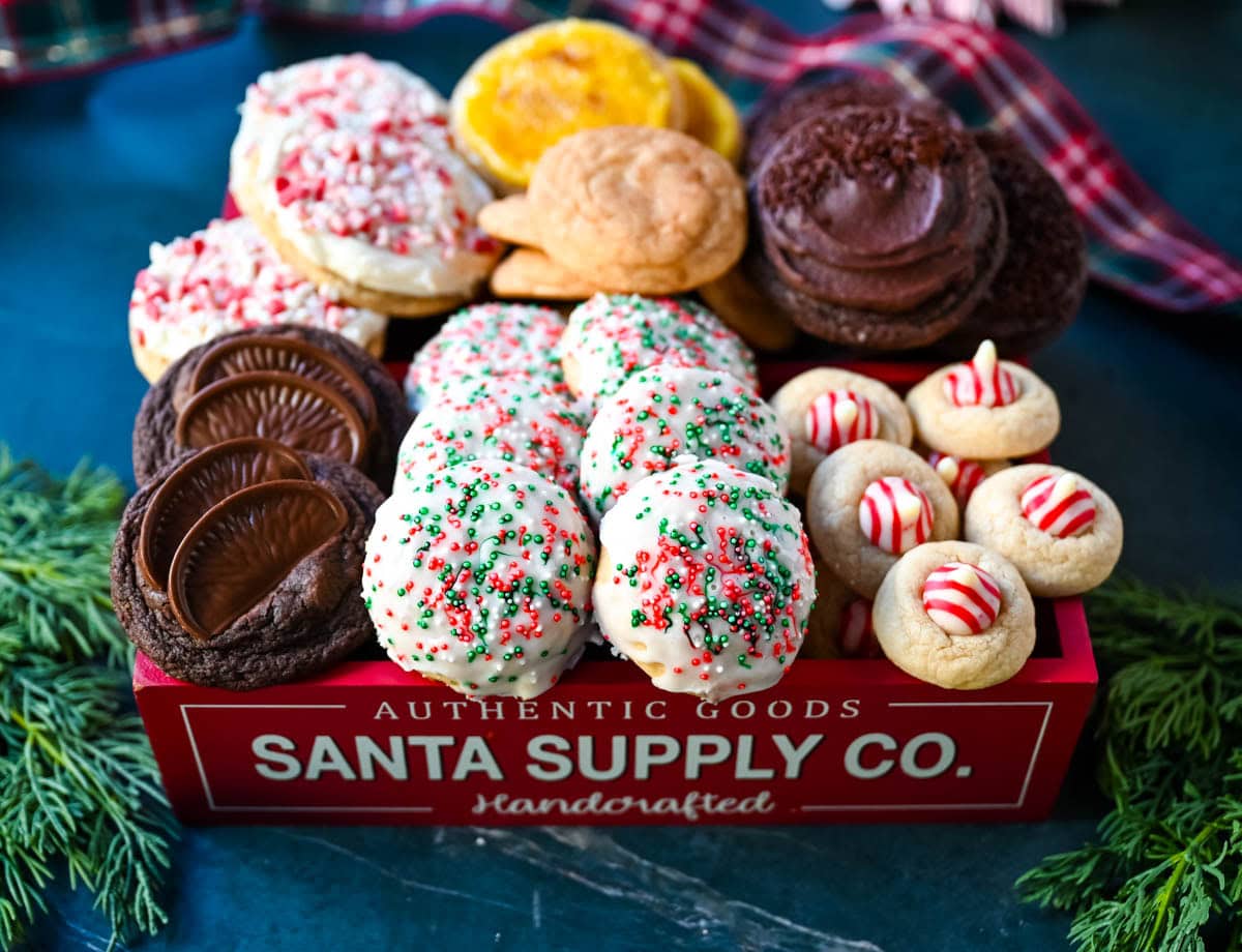 These Candy Cane Kiss Cookies are soft, buttery sugar cookies rolled in sparkling sugar or festive sprinkles, baked until just set, and then pressed with a striped peppermint Candy Cane Kiss right in the center. This Peppermint Kiss Cookie is such a festive Christmas cookie recipe. Candy Cane Kiss Cookies in Christmas Cookie Box.