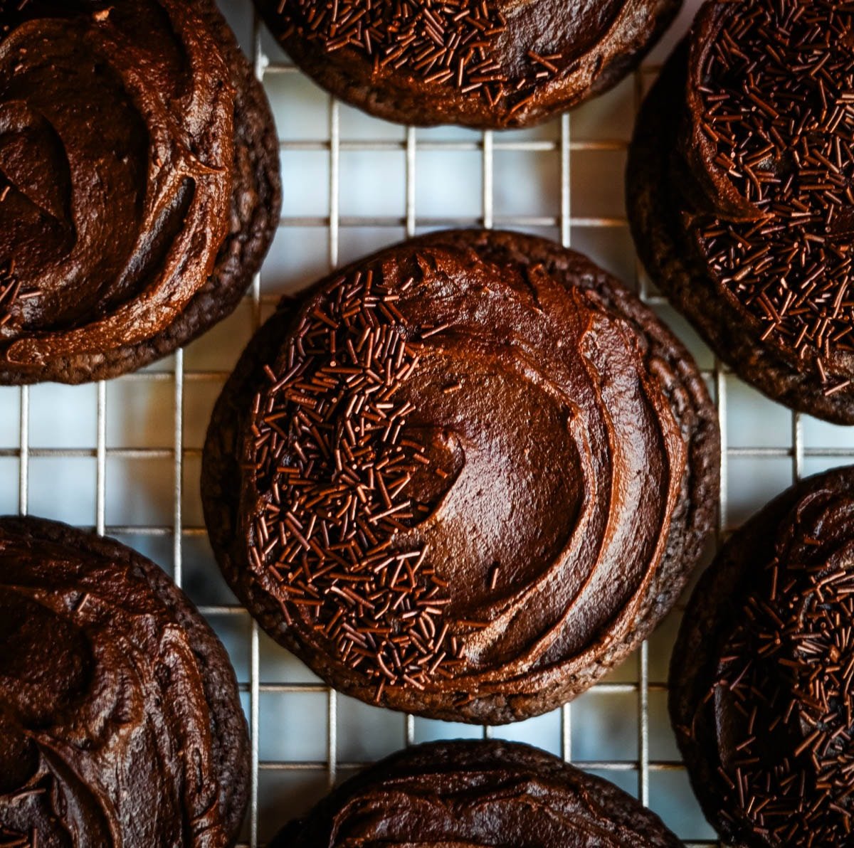 These easy Chocolate Frosted Cookies combine soft chocolate cookies with a rich, chocolate buttercream frosting. The double chocolate cookie base is filled with melty chocolate chips and a smooth cocoa frosting on top. These Frosted Chocolate Cookies are a chocolate lover’s dream.