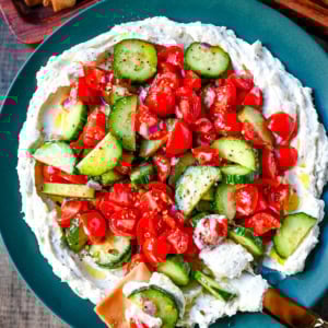 This Greek feta dip is the ultimate party and holiday appetizer that is rich, creamy, and so flavorful! It blends tangy feta, cream cheese, lemon, oregano, and olive oil into a silky whipped dip that feels fancy but takes just minutes to make. Pile it high with tomatoes, cucumbers, and a drizzle of olive oil, then serve with pita chips or veggies.