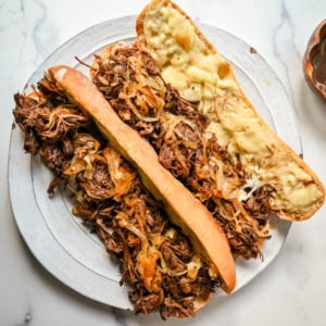 This easy slow cooker French dip sandwich recipe features tender beef, savory au jus, caramelized onions, and melted provolone cheese. Finished with a creamy horseradish aioli, it’s a restaurant-quality sandwich made right at home.