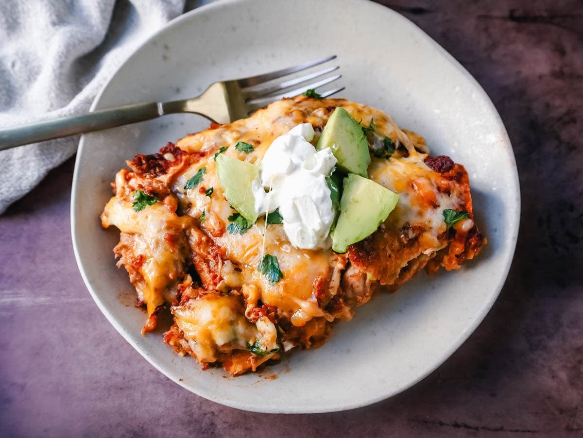 Chicken enchiladas with red sauce are made with soft, savory corn tortillas, shredded chicken, warm, flavorful red sauce from scratch, and topped with Mexican crema and cheese.
