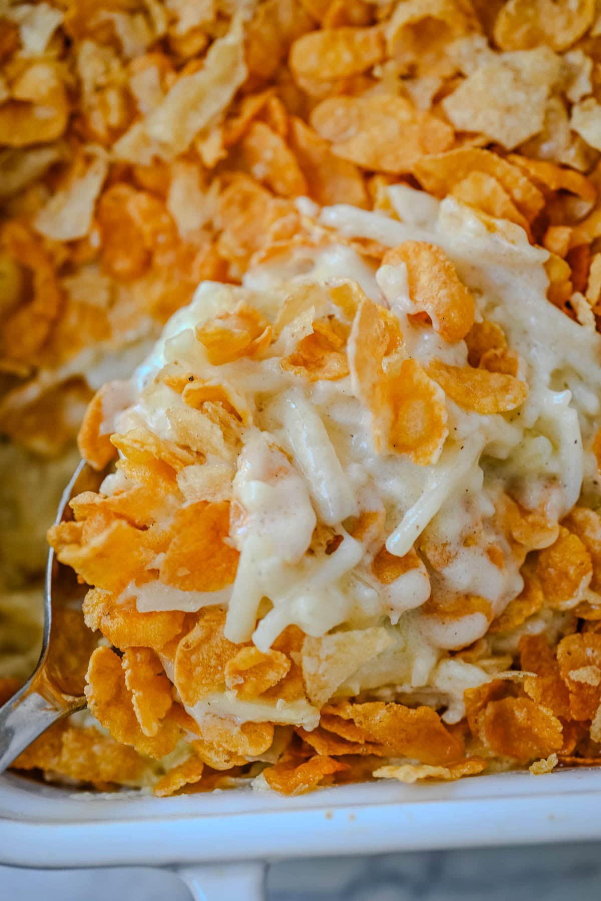 This creamy, cheesy funeral potatoes recipe is the ultimate comfort food casserole made with hash browns, sour cream, cheddar, and a rich homemade sauce. Topped with a crispy cornflake and potato chip crust, it’s perfect for Easter, potlucks, and family dinners. Learn how to make the best funeral potatoes from scratch -- no canned soup needed.