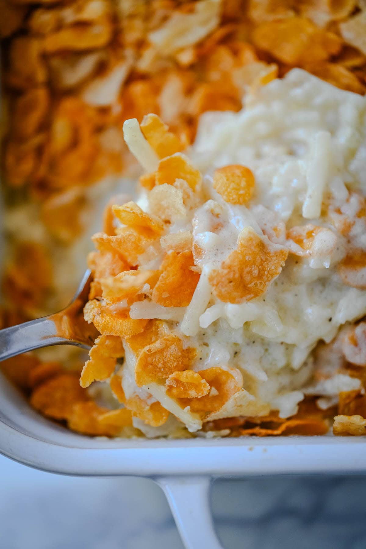 This creamy, cheesy funeral potatoes recipe is the ultimate comfort food casserole made with hash browns, sour cream, cheddar, and a rich homemade sauce. Topped with a crispy cornflake and potato chip crust, it’s perfect for Easter, potlucks, and family dinners. Learn how to make the best funeral potatoes from scratch -- no canned soup needed.