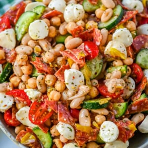 This Italian dense bean salad is the TikTok viral high protein meal prep recipe that has taken over the internet and for very good reason. Loaded with chickpeas, white beans, crisp Persian cucumbers, cherry tomatoes, creamy mozzarella, savory pepperoni or salami, and tangy pepperoncinis all tossed in a homemade Italian dressing, every single bite is packed with incredible flavor that gets better the longer it sits.