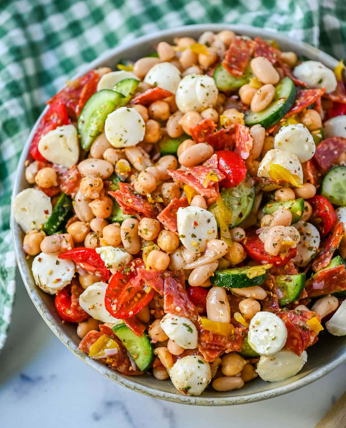 This Italian dense bean salad is the TikTok viral high protein meal prep recipe that has taken over the internet and for very good reason. Loaded with chickpeas, white beans, crisp Persian cucumbers, cherry tomatoes, creamy mozzarella, savory pepperoni or salami, and tangy pepperoncinis all tossed in a homemade Italian dressing, every single bite is packed with incredible flavor that gets better the longer it sits.