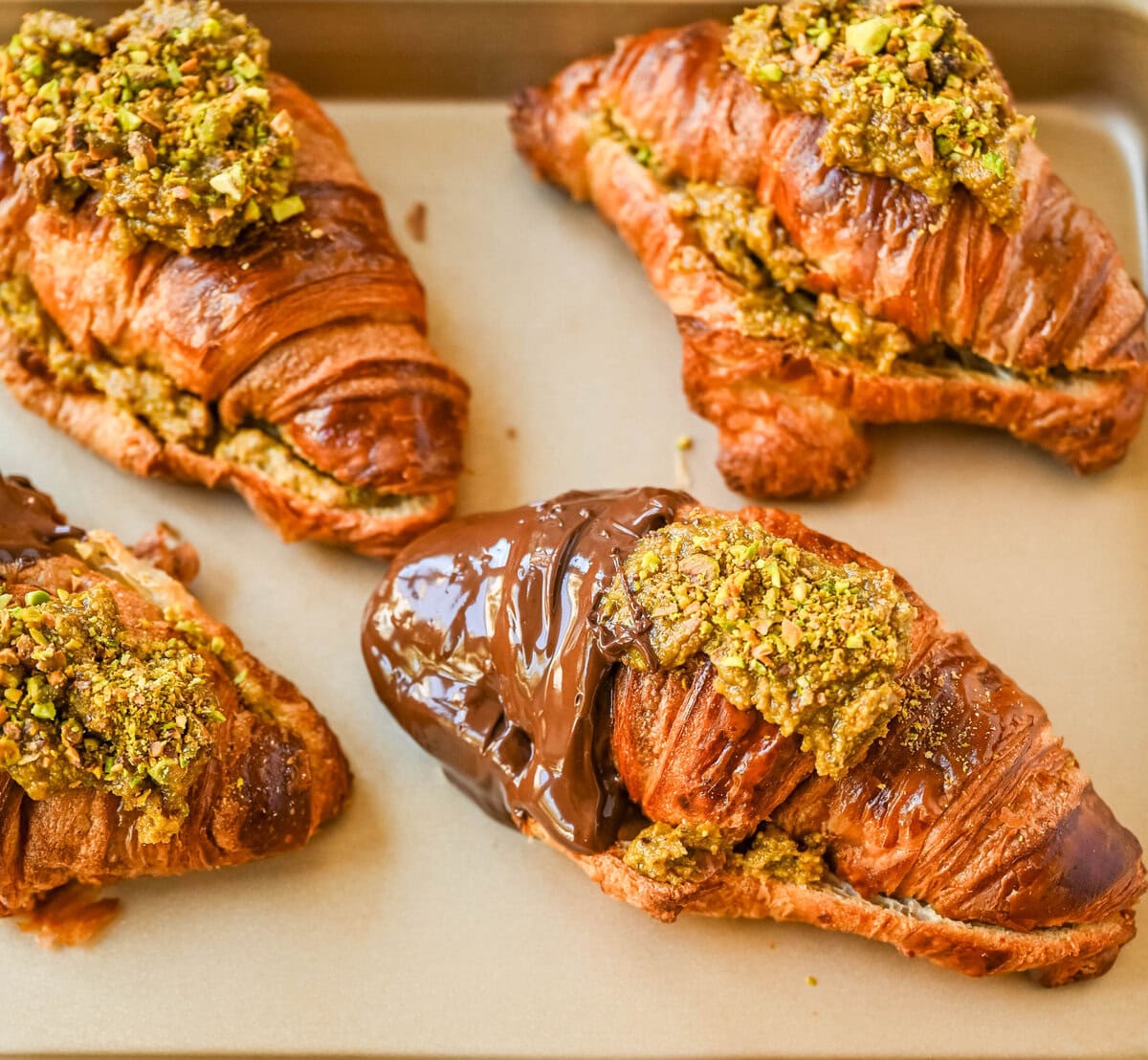 Make your own Pistachio Croissants dipped in chocolate at home in just a few easy steps! Buttery croissants are stuffed with a creamy pistachio cream filling and topped with a simple syrup and chopped pistachios for crunch. The easiest Pistachio chocolate Croissant recipe made in less than 30 minutes!