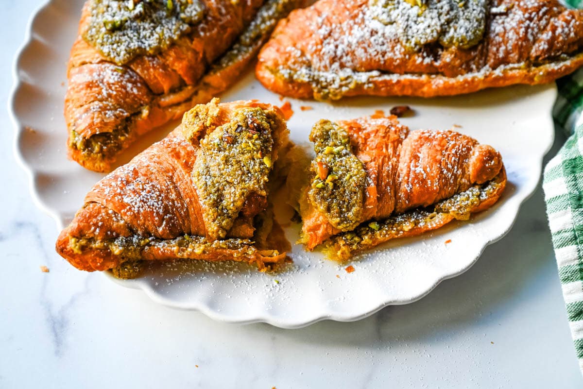 Make your own Pistachio Croissants at home in just a few easy steps! Buttery croissants are stuffed with a creamy pistachio cream filling and topped with a simple syrup and chopped pistachios for crunch. The easiest Pistachio Croissant recipe made in less than 30 minutes!