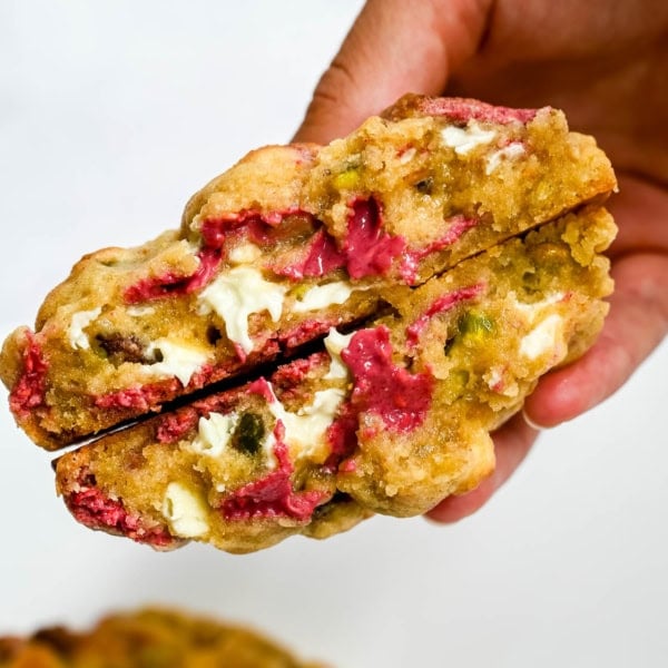 These Levain Bakery Raspberry Pistachio cookies are a homemade copycat of Levain Bakery's new summer flavor, which combines raspberry chips, crunchy pistachios, and creamy white chocolate chips in their signature thick, bakery-style cookie. Our version uses a homemade raspberry chip made from crushed freeze-dried raspberries and white chocolate for that same fruity flavor without needing specialty baking chips. These cookies are thick, gooey, and loaded with tart raspberry, rich white chocolate, and crunchy salted pistachios in every bite!
