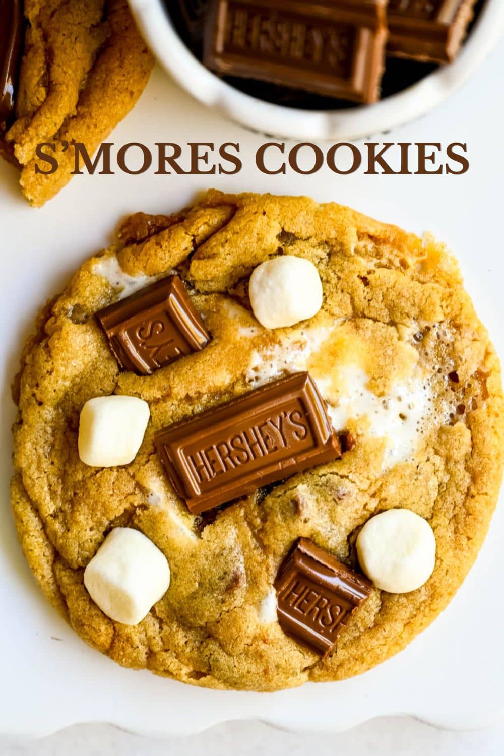 The best s'mores cookie recipe made with graham cracker dough, Hershey's chocolate, and marshmallows baked in and piled on top. These homemade smores cookies are ooey, chewy, and so easy. This easy s'mores cookie recipe comes together in just one bowl.
