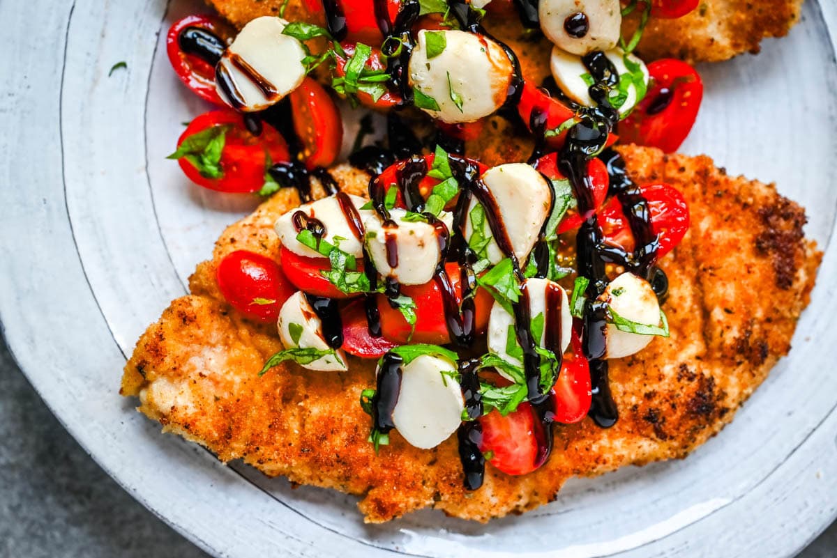 Crispy Caprese Chicken is crispy panko-crusted chicken topped with a fresh grape tomato and mozzarella caprese salad, finished with balsamic glaze. A simple, restaurant-worthy dinner ready in 30 minutes.