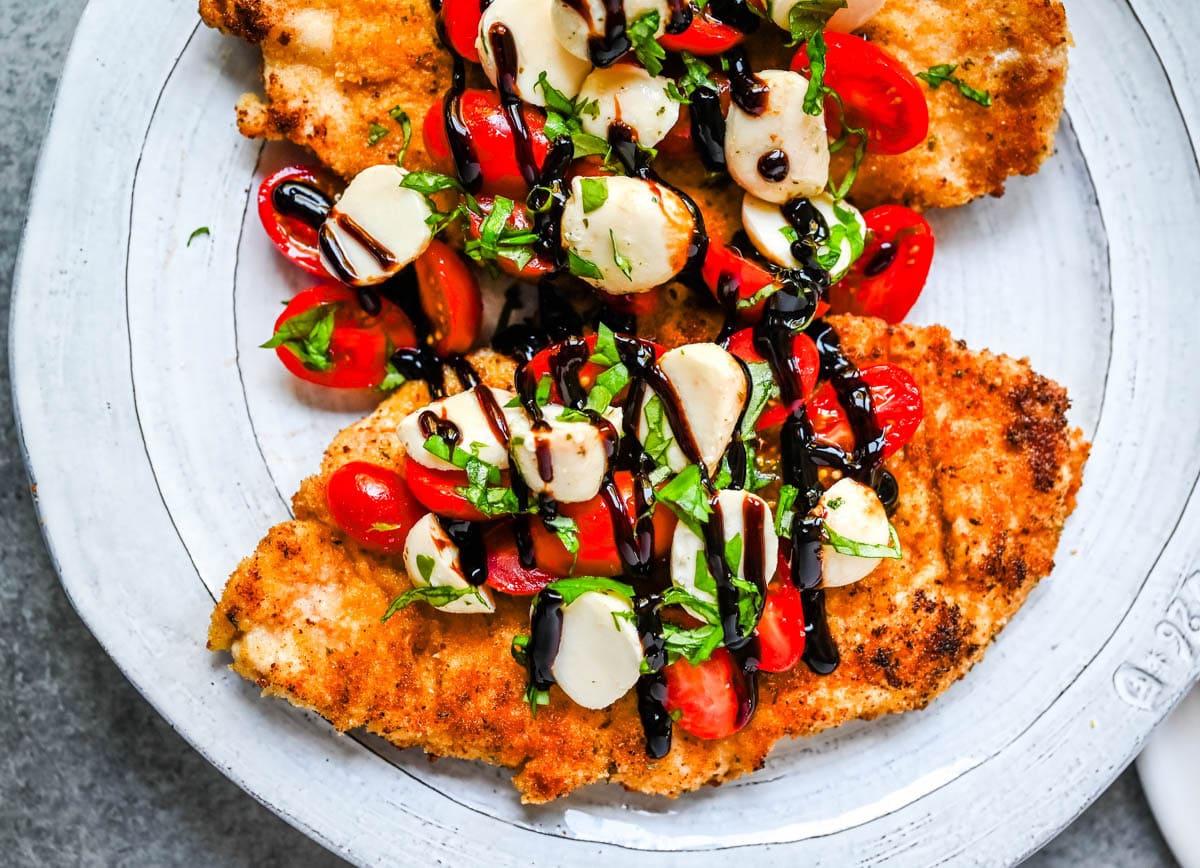 Crispy Caprese Chicken is crispy panko-crusted chicken topped with a fresh grape tomato and mozzarella caprese salad, finished with balsamic glaze. A simple, restaurant-worthy dinner ready in 30 minutes.