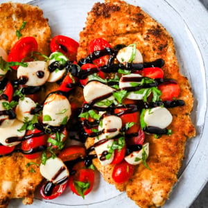 Crispy Caprese Chicken is crispy panko-crusted chicken topped with a fresh grape tomato and mozzarella caprese salad, finished with balsamic glaze. A simple, restaurant-worthy dinner ready in 30 minutes.