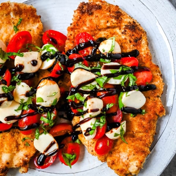 Crispy Caprese Chicken is crispy panko-crusted chicken topped with a fresh grape tomato and mozzarella caprese salad, finished with balsamic glaze. A simple, restaurant-worthy dinner ready in 30 minutes.