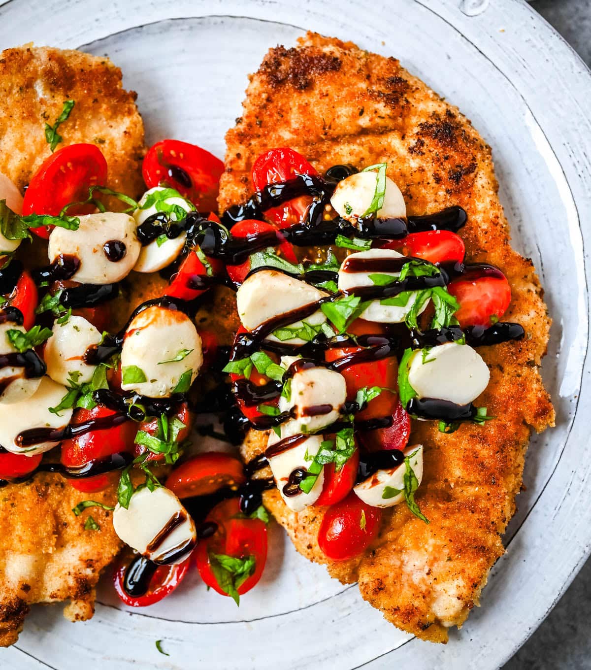 Crispy Caprese Chicken is crispy panko-crusted chicken topped with a fresh grape tomato and mozzarella caprese salad, finished with balsamic glaze. A simple, restaurant-worthy dinner ready in 30 minutes.