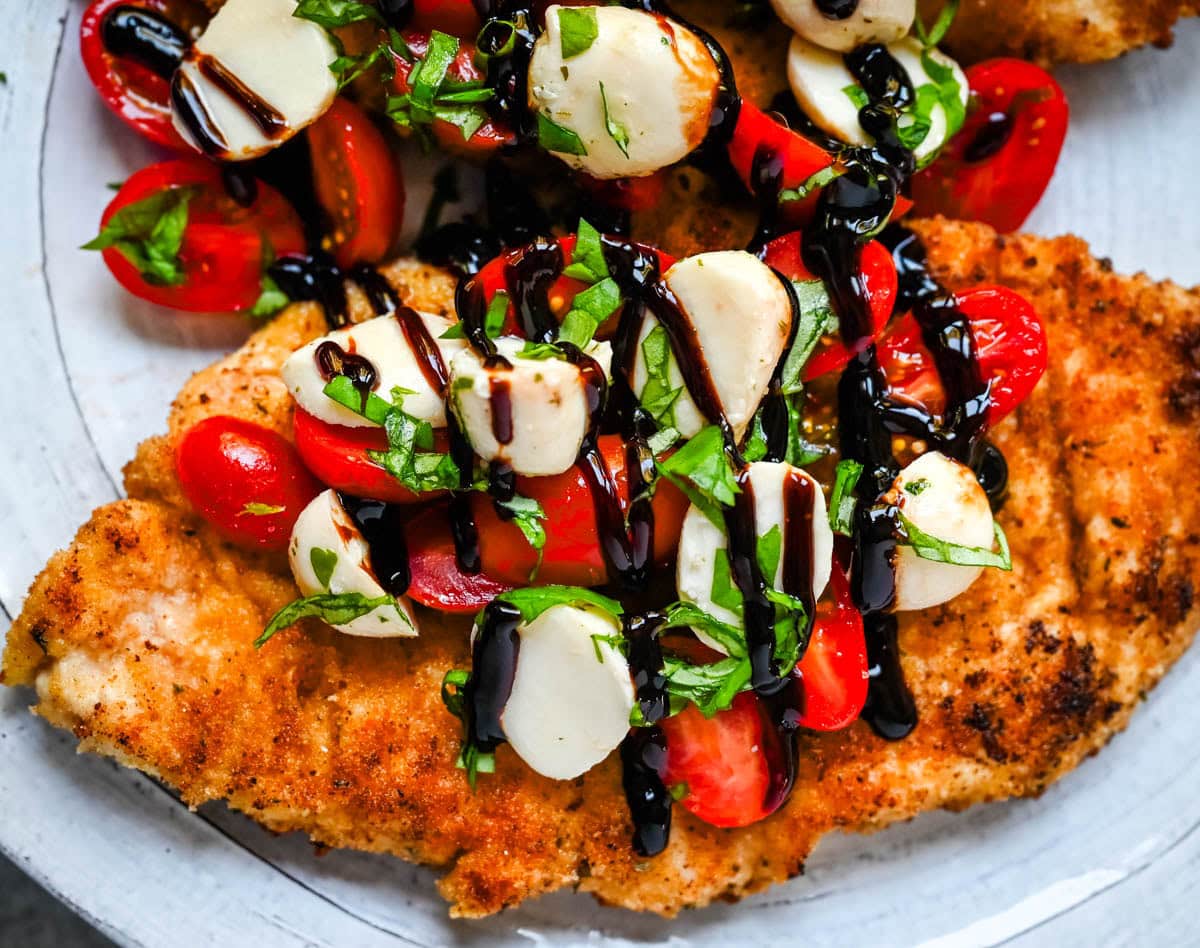 Crispy Caprese Chicken is crispy panko-crusted chicken topped with a fresh grape tomato and mozzarella caprese salad, finished with balsamic glaze. A simple, restaurant-worthy dinner ready in 30 minutes.