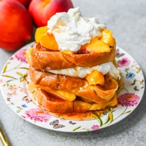 This Peaches and Cream French toast is made with thick slices of challah or brioche bread soaked in a rich, creamy custard, then topped with fresh whipped cream, juicy peaches, and real maple syrup. It's the ultimate easy peach French toast recipe.