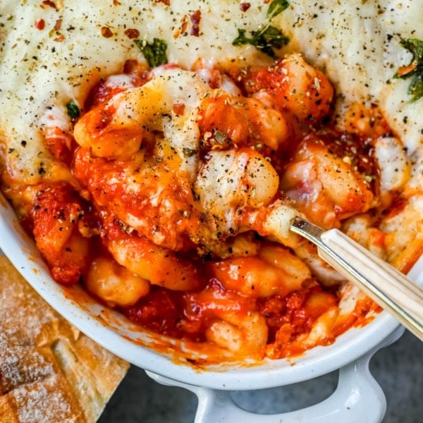 This cheesy baked gnocchi is made with pillowy gnocchi tossed in marinara sauce, layered with mozzarella and parmesan, and baked until golden and bubbly. Topped with fresh basil, this easy gnocchi bake comes together in one dish and tastes like it took hours.