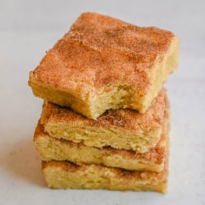 These snickerdoodle bars have all the soft, chewy, cinnamon-sugar flavor of classic snickerdoodle cookies, baked in one pan for an easier, faster version. No scooping, no rolling — just press, sprinkle, and bake for a crowd-sized batch of snickerdoodle flavor in every bite.