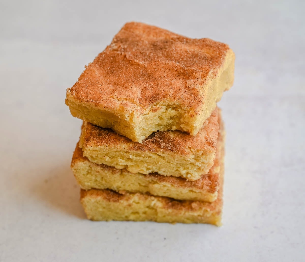 These snickerdoodle bars have all the soft, chewy, cinnamon-sugar flavor of classic snickerdoodle cookies, baked in one pan for an easier, faster version. No scooping, no rolling — just press, sprinkle, and bake for a crowd-sized batch of snickerdoodle flavor in every bite.