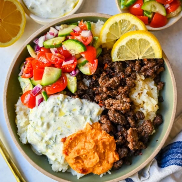 Greek Beef Bowls. Juicy seasoned ground beef, bright lemon rice, feta, cucumbers, tomatoes and tzatziki in one easy 35-minute dinner. High-protein bowls that hold up all week for lunches.