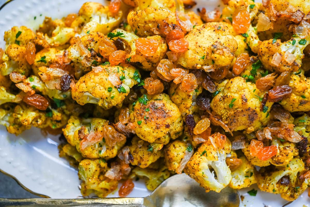 Indian Roasted Cauliflower with Golden Raisins and Pine Nuts. Golden, tender turmeric and curry roasted cauliflower tossed with sweet caramelized onion, golden raisins, and pine nuts. An easy vegan-friendly side.