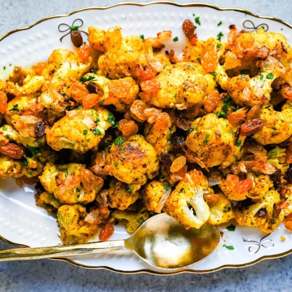 Indian Roasted Cauliflower with Golden Raisins and Pine Nuts. Golden, tender turmeric and curry roasted cauliflower tossed with sweet caramelized onion, golden raisins, and pine nuts. An easy vegan-friendly side.