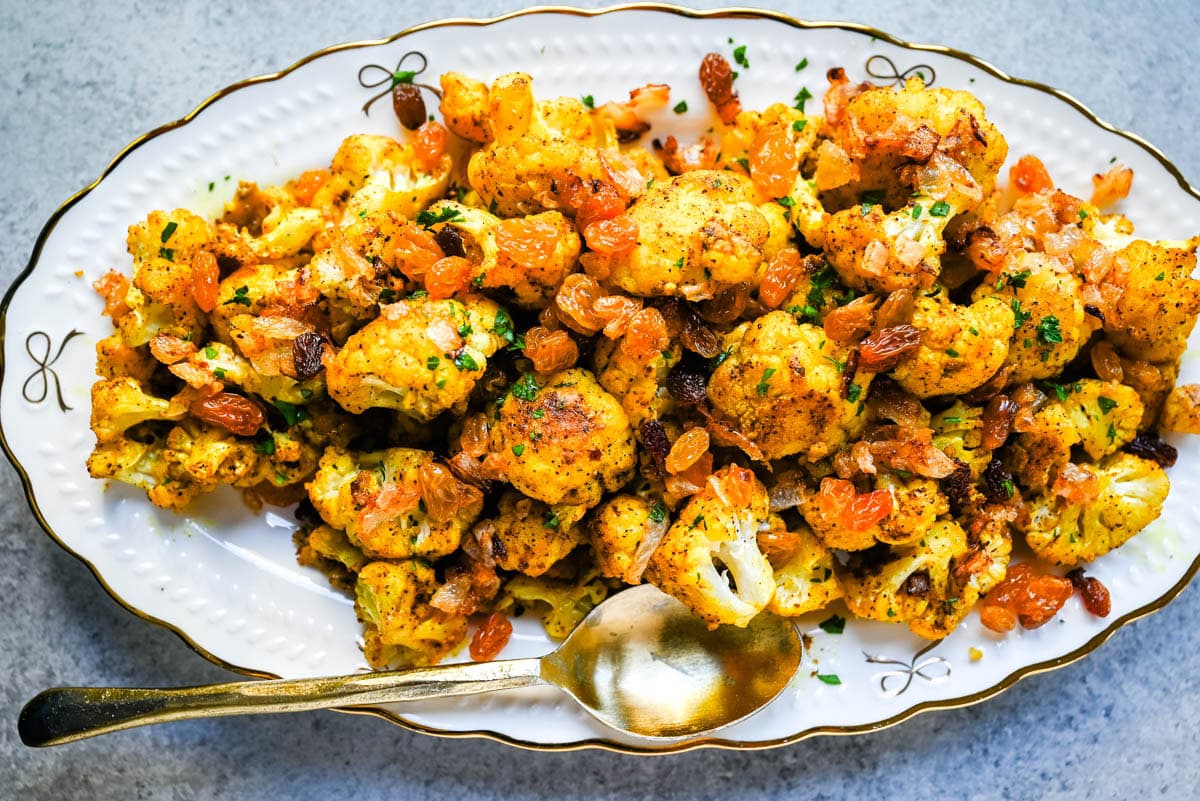 Indian Roasted Cauliflower with Golden Raisins and Pine Nuts. Golden, tender turmeric and curry roasted cauliflower tossed with sweet caramelized onion, golden raisins, and pine nuts. An easy vegan-friendly side.