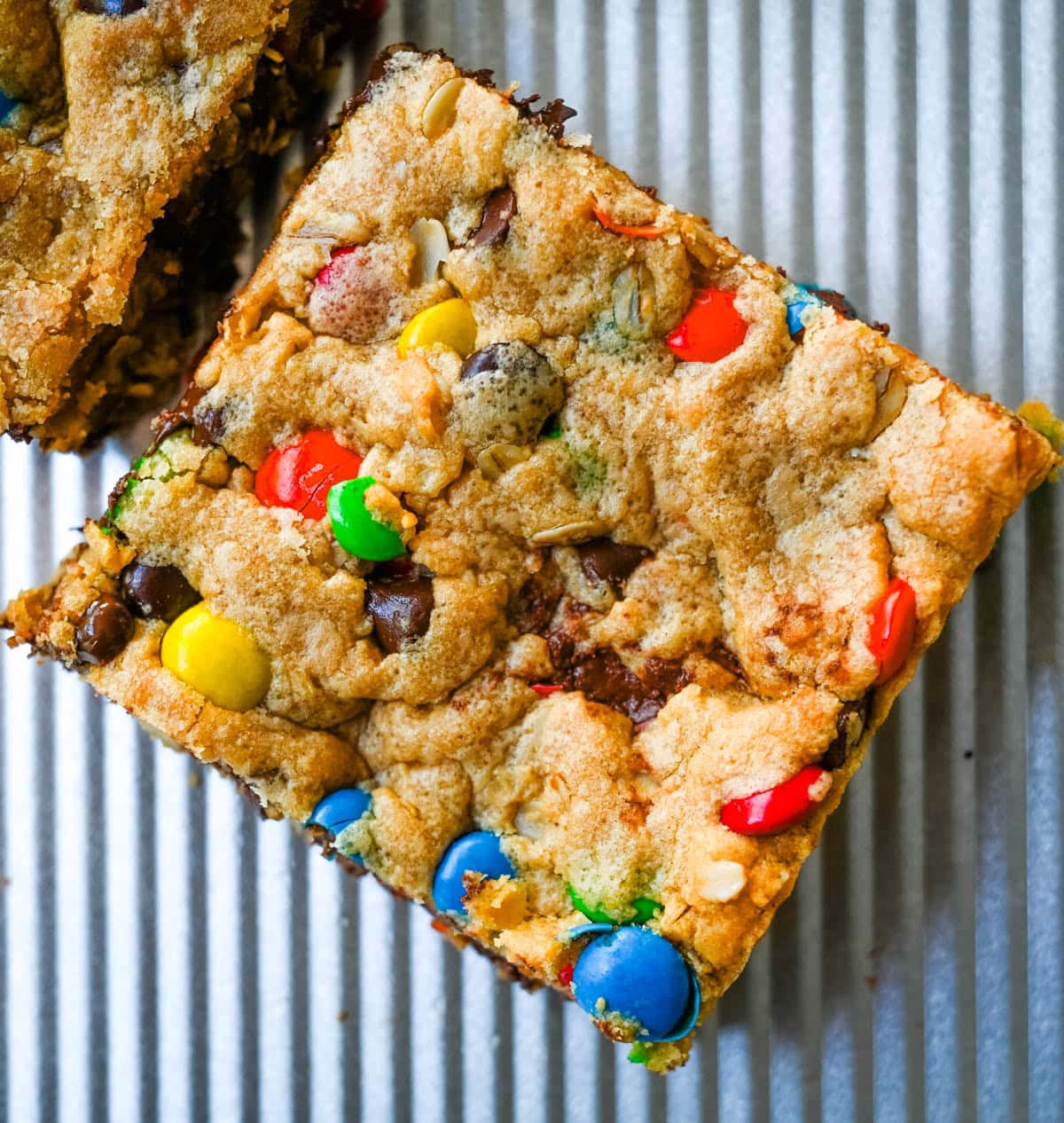 Monster Cookie Bars are thick, chewy peanut butter oatmeal bars loaded with M&M’s and chocolate chips. One bowl, one 9x13 pan, and no scooping!